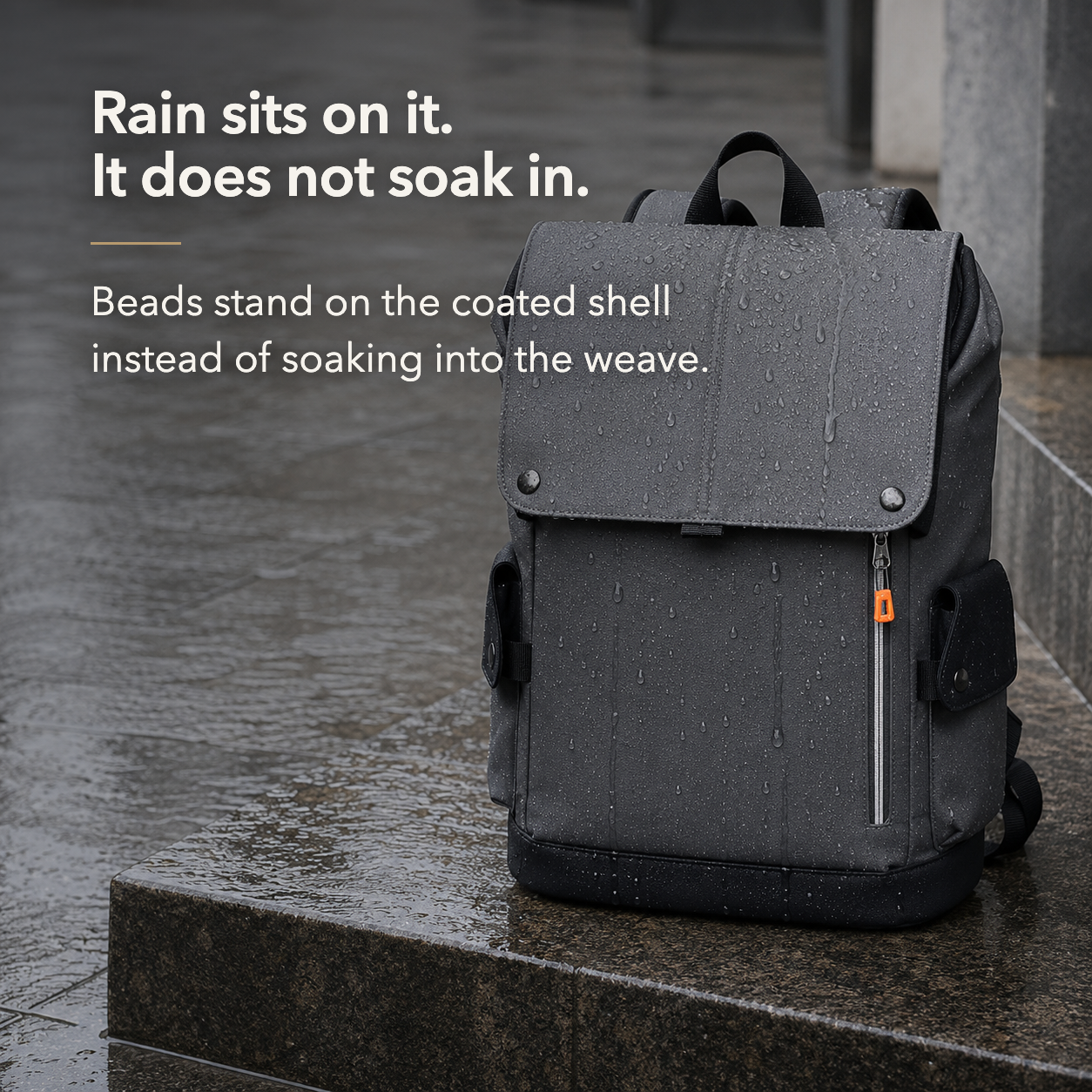 Rain standing in separate beads on the coated surface of the dark gray backpack outdoors