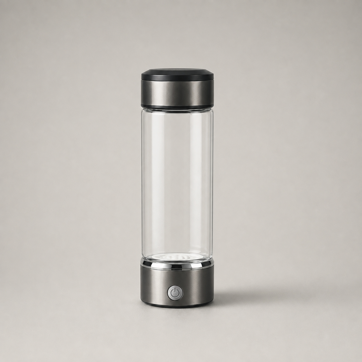 The empty bottle on plain grey: a metal lid, a clear barrel with nothing in it, and a metal base collar with one round button