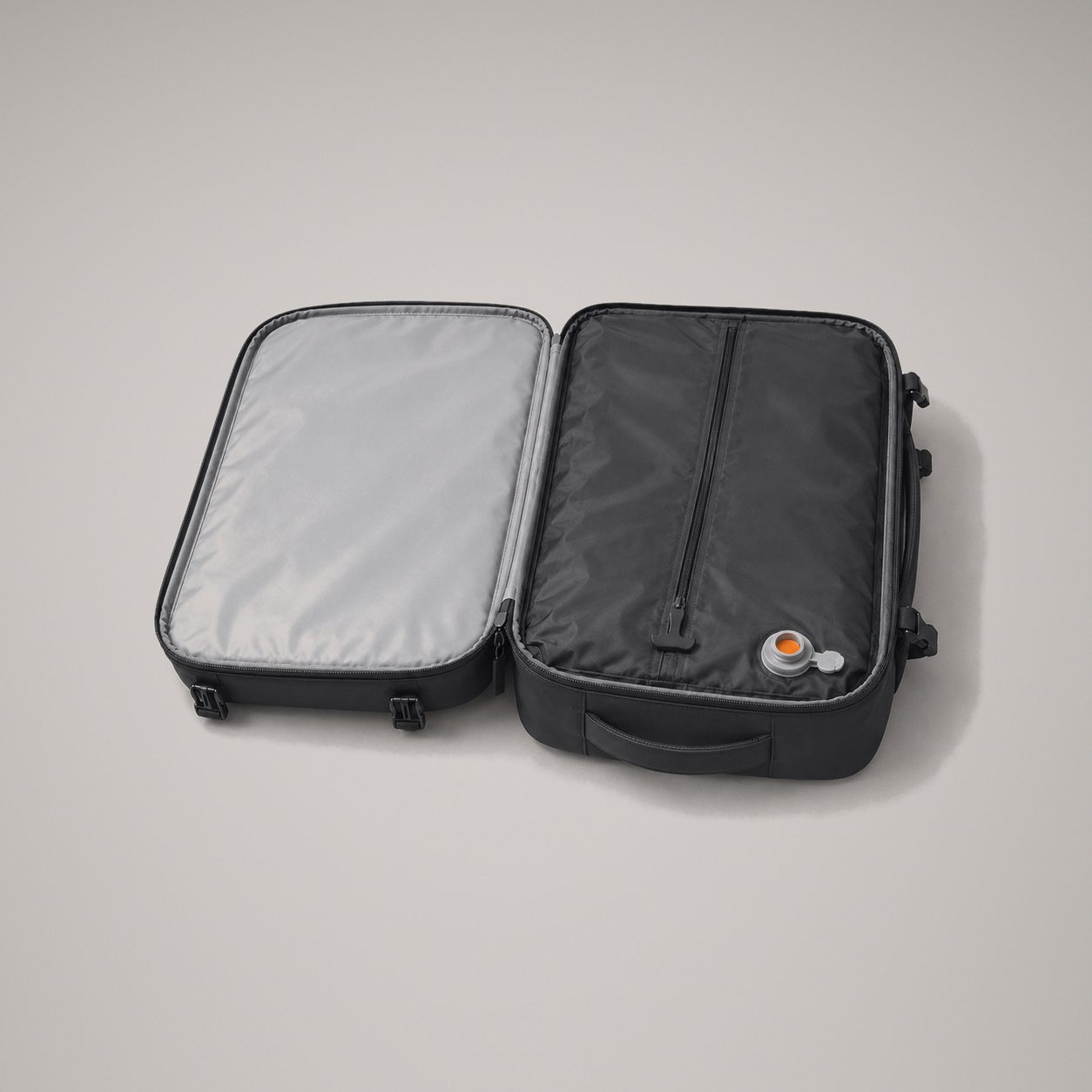The backpack opened flat through 180 degrees on a grey studio background, showing the plain grey lined lid and the sealed black compression chamber with its single zip and grey air valve