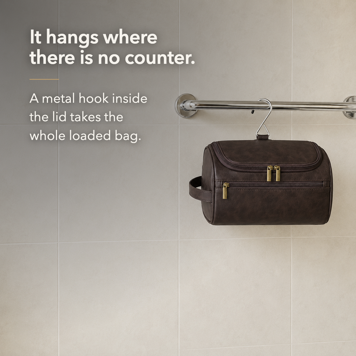 Dark Brown toiletry bag hanging closed from a chrome towel rail by its wire hanger hook, below the words It hangs where there is no counter