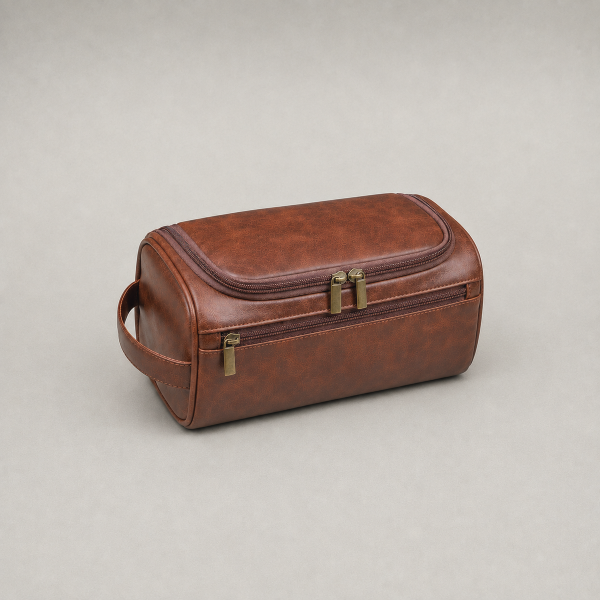Brown hanging toiletry bag closed, front three quarter view on a plain grey studio background
