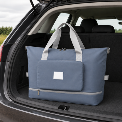 Blue foldable travel bag in an open car boot in daylight, with pale grey webbing carry handles