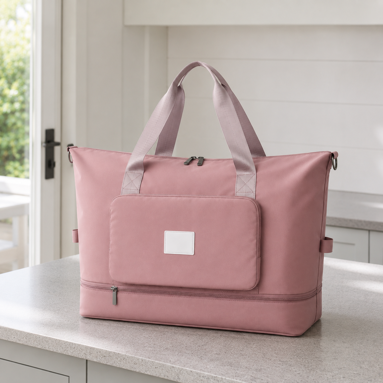 Pink foldable travel bag on a kitchen worktop in daylight, with mauve webbing carry handles