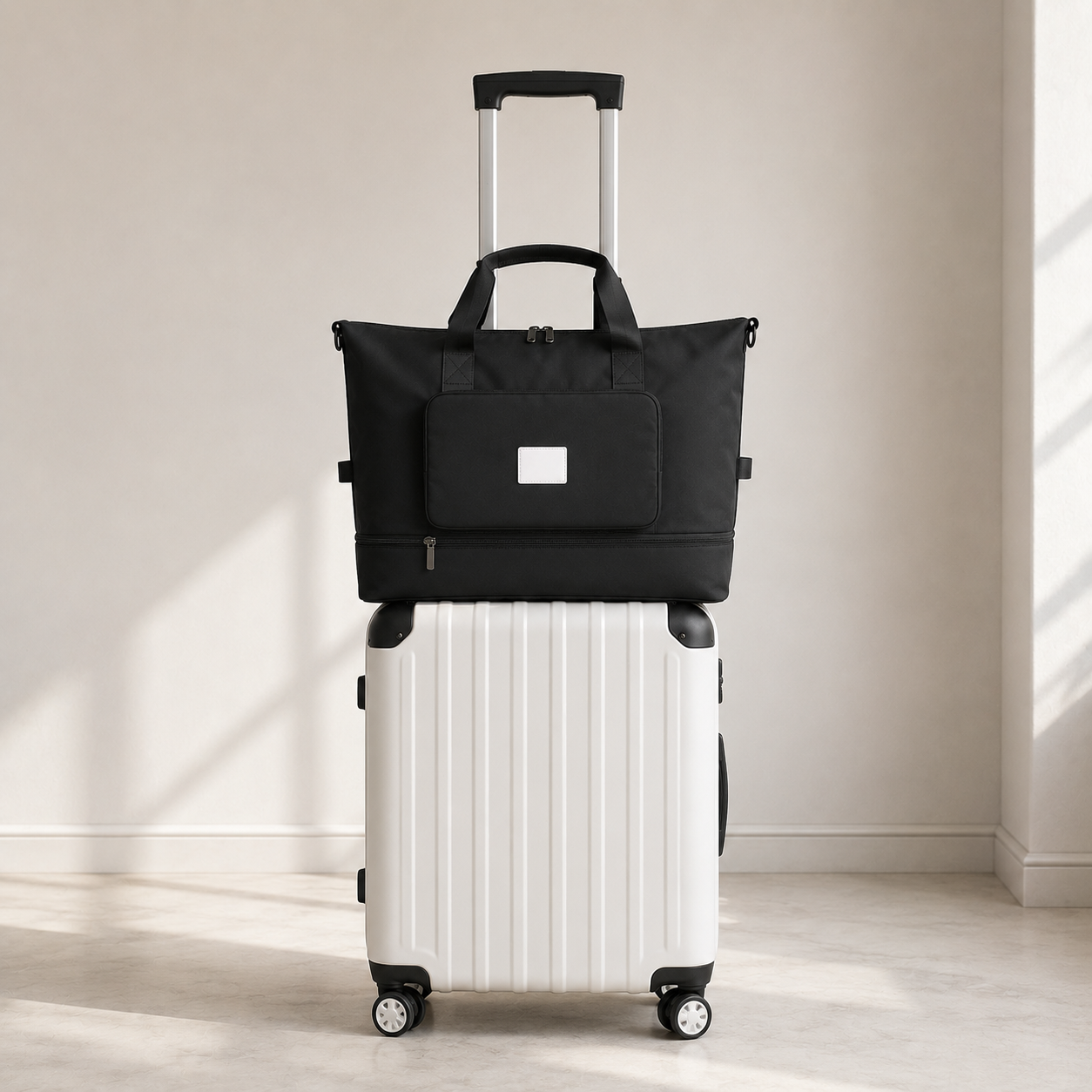 Black foldable travel bag threaded onto the extended pull handle of a white wheeled suitcase, the handle tubes passing behind the bag