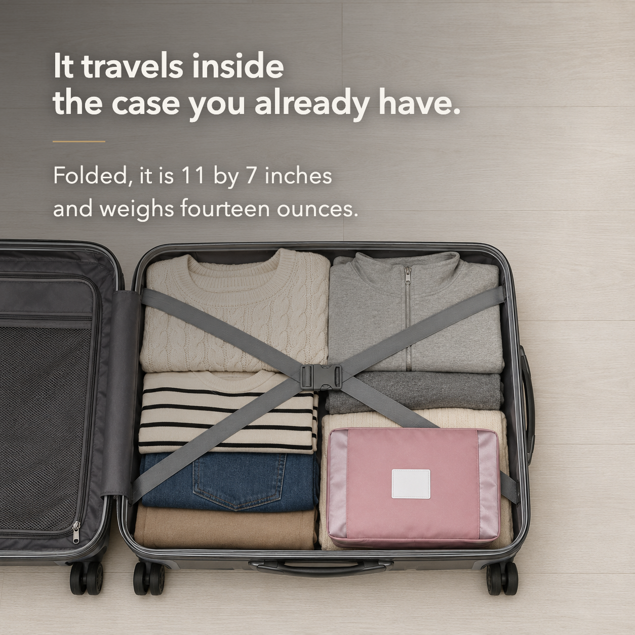 Pink travel bag folded flat and packed among clothes in an open suitcase, below the words It travels inside the case you already have