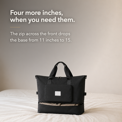 Black travel bag on a bed with its base zipped open and expanded, below the words Four more inches, when you need them