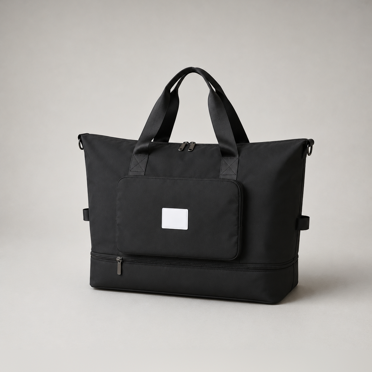 Black foldable travel bag closed, front view on a plain grey studio background