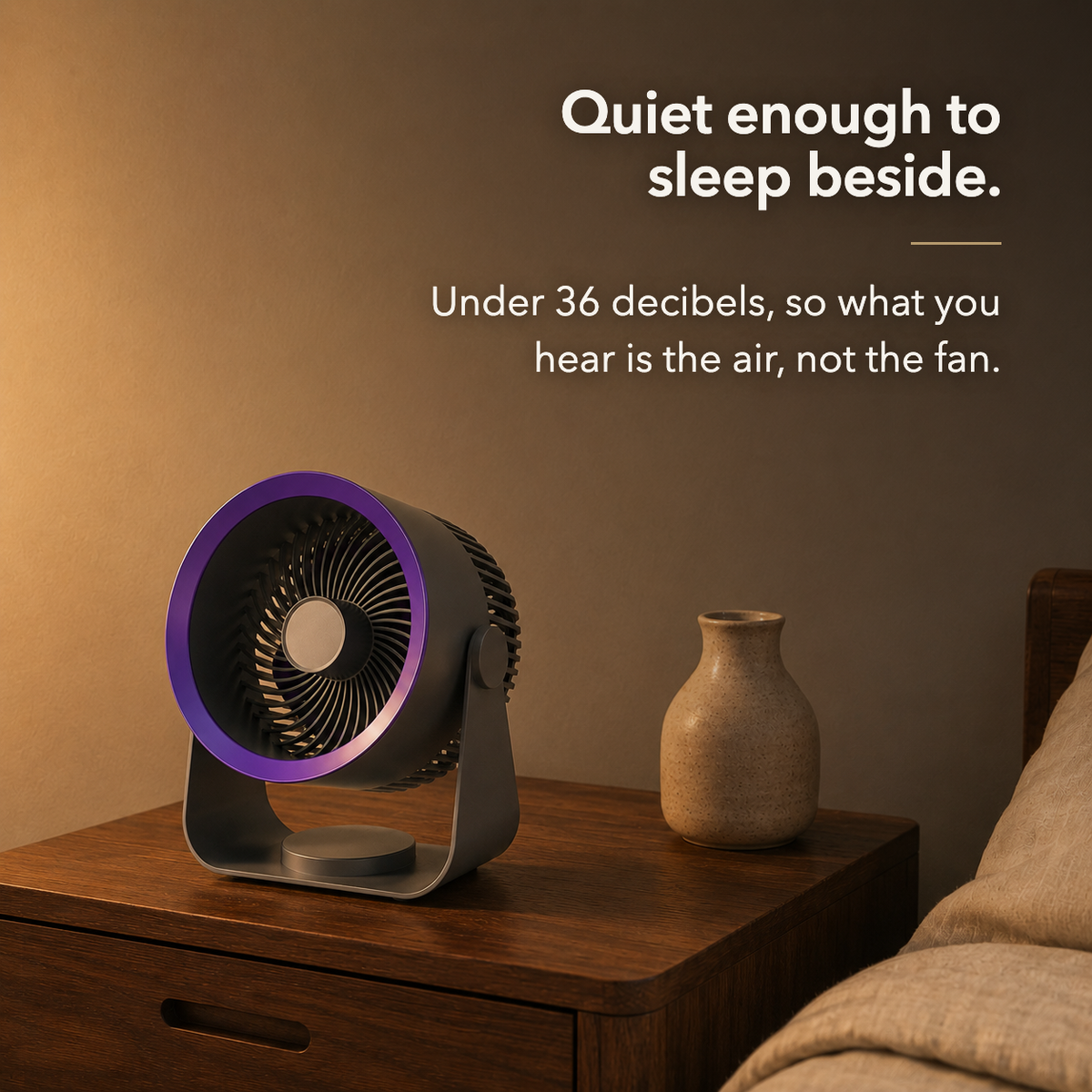 Air circulator fan on a wooden bedside table in warm evening light, with the text: Quiet enough to sleep beside. Under 36 decibels, so what you hear is the air, not the fan.