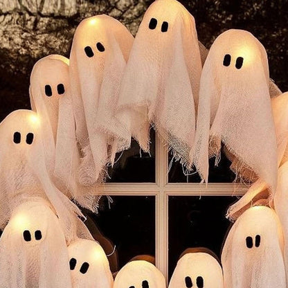 Lit ghost heads over a dark window pane at night, showing the frayed cloth hems