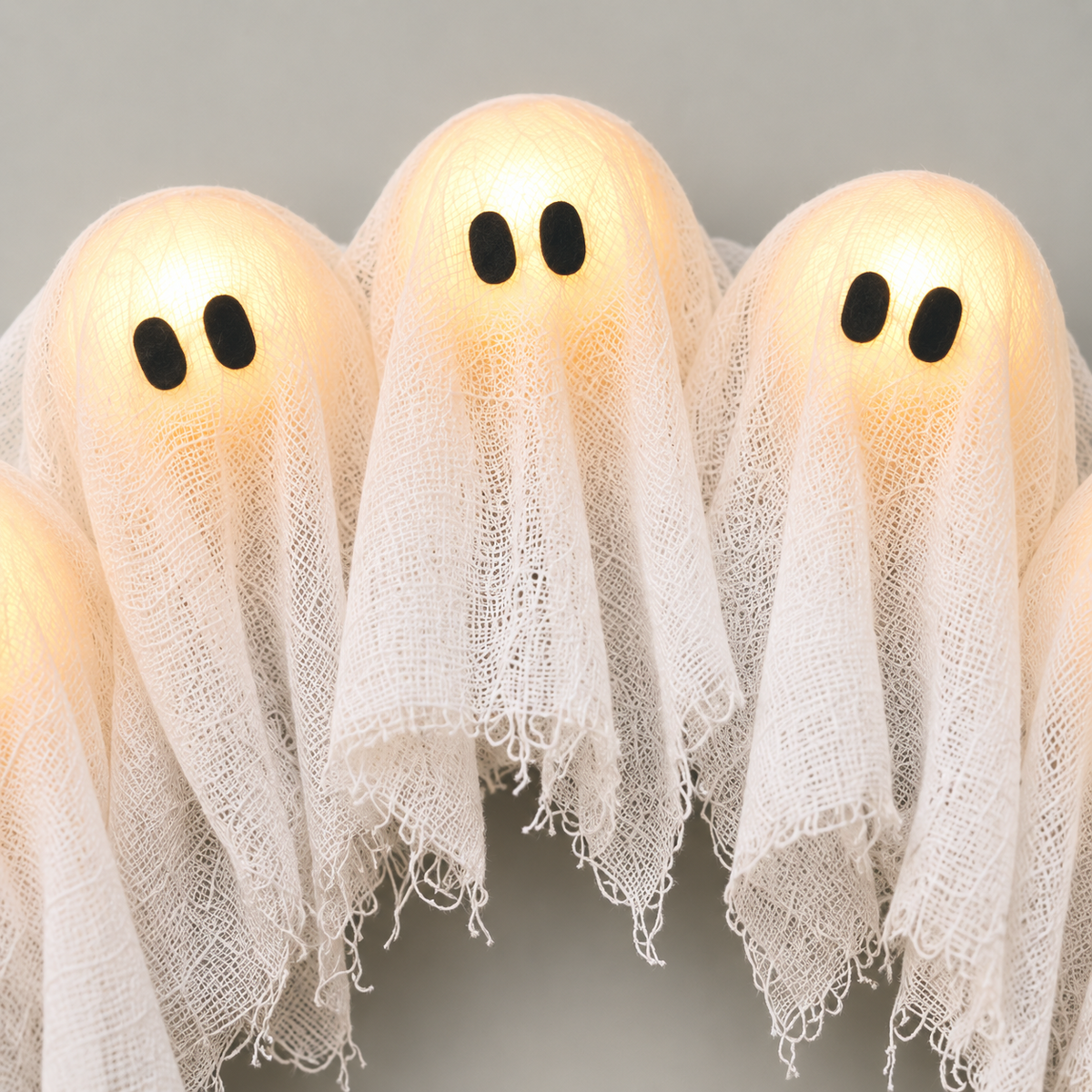 Close view of two ghost heads showing the open weave cloth and the black felt eyes