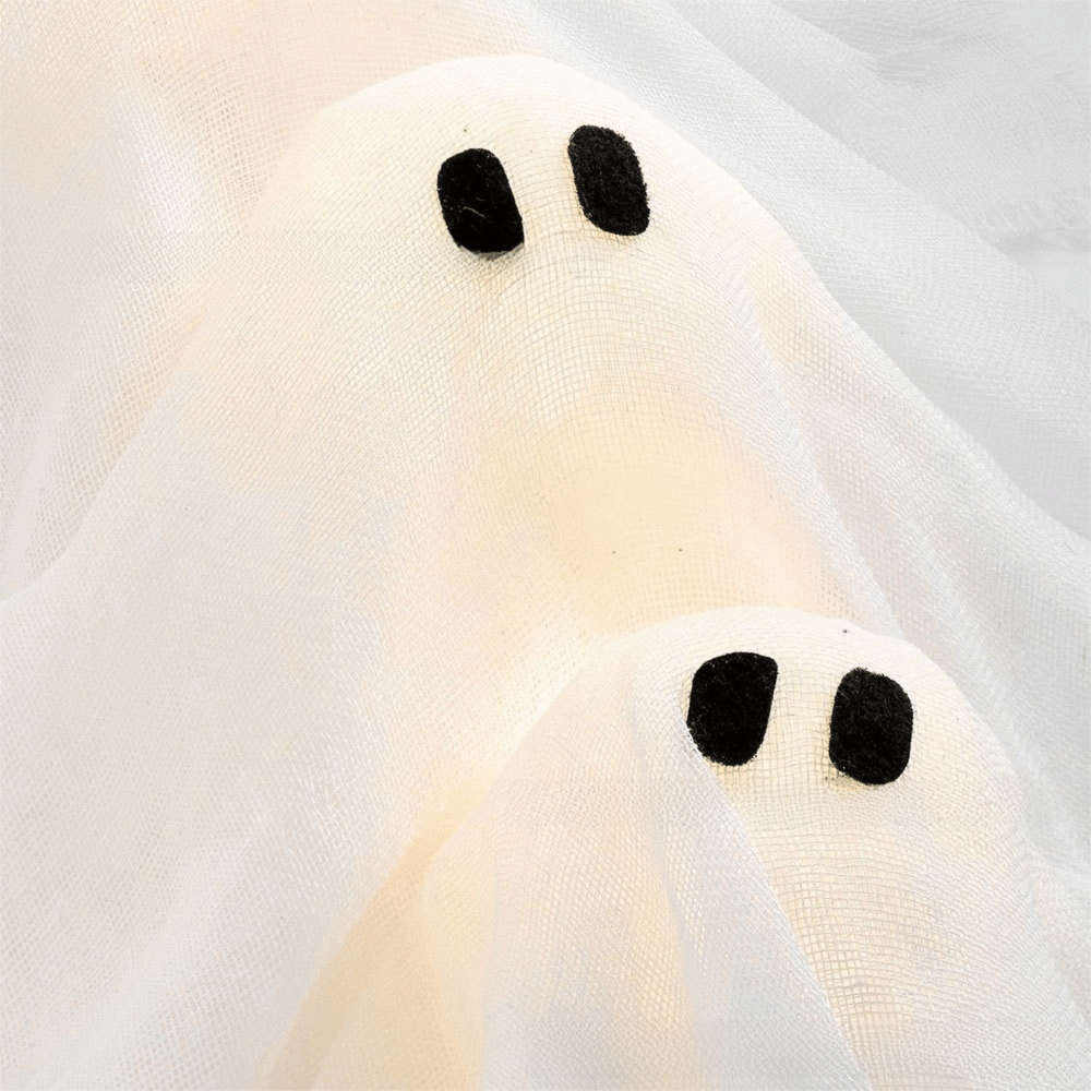 Close view of two lit ghost heads showing the woven cloth and the felt eyes