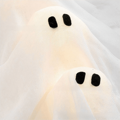 Close view of two lit ghost heads showing the woven cloth and the felt eyes