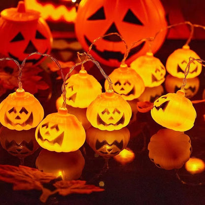 Pumpkin string lights lit warm white beside a large carved pumpkin bucket at night