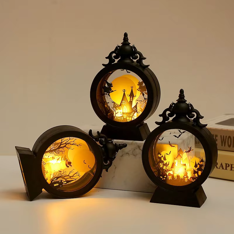 Three lit Halloween lanterns with one tipped onto its side, showing the outer drum, the solid back and the base