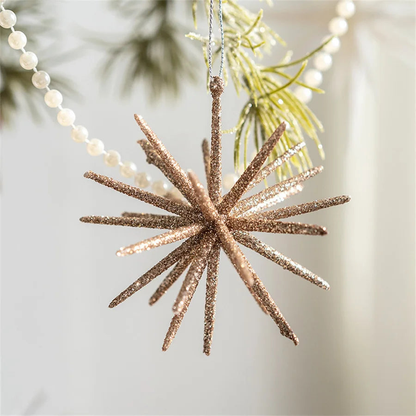Small champagne starburst ornament hanging beside a pearl garland and pine