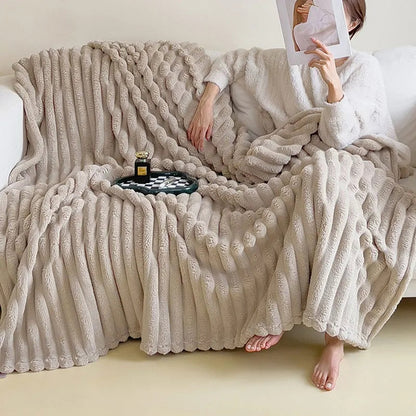 Beige pleated faux fur throw spread over a white sofa, with someone reading under one end