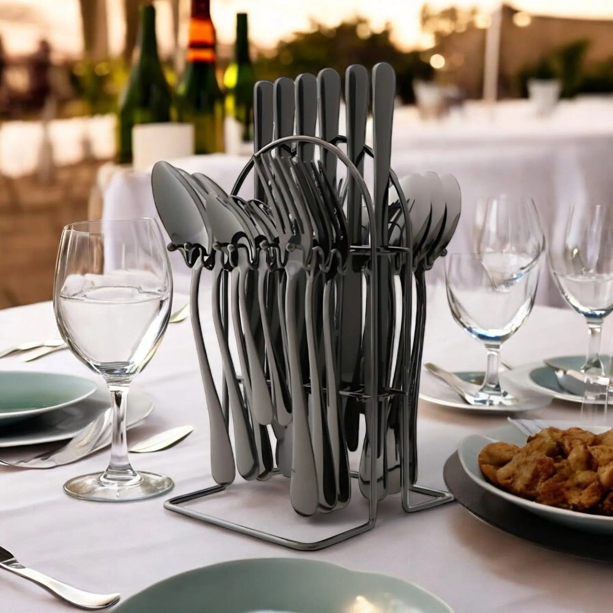 Black cutlery set hanging on a black arched rack on a dinner table set with glasses and plates