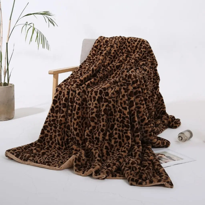 A camel leopard print throw blanket with dark brown spots on a tan ground, draped over a wooden armchair.