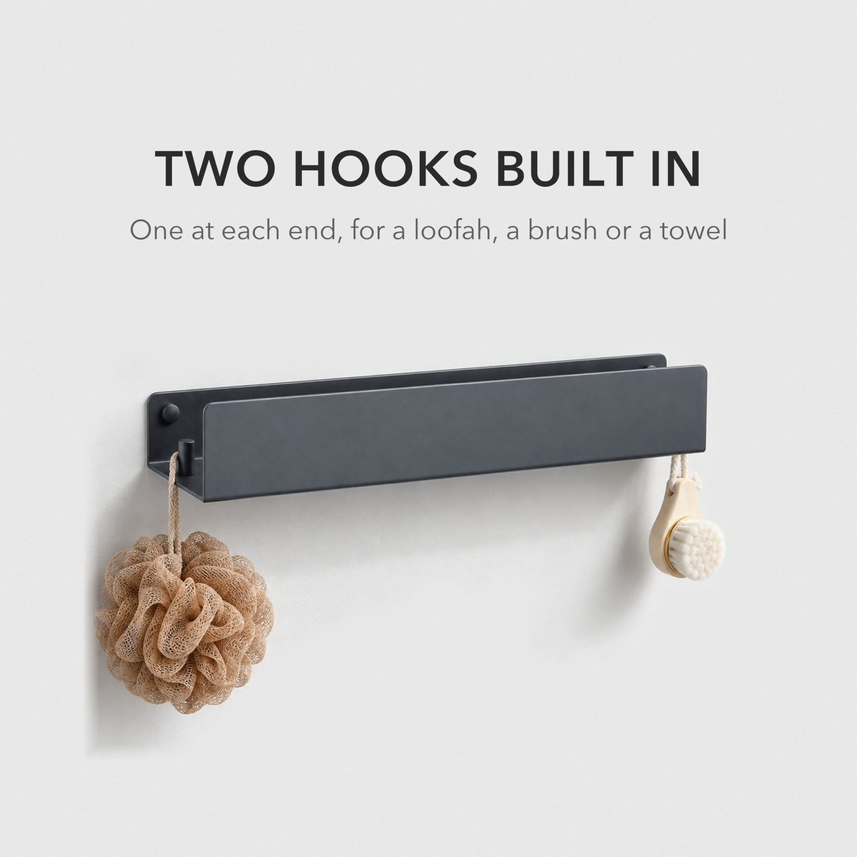 Black bathroom shelf on a grey wall with a loofah and a face brush hanging from the hook pegs at each end