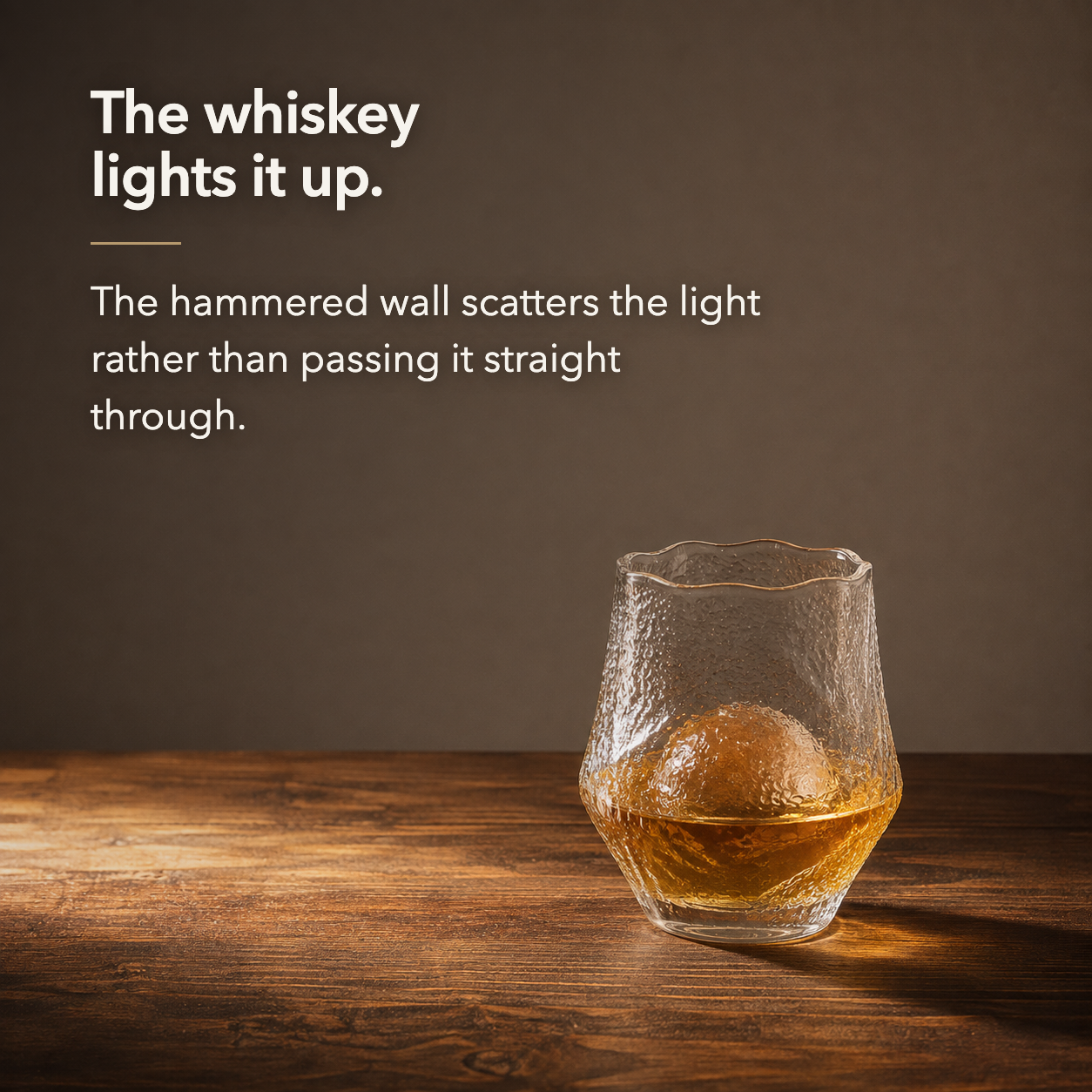Whiskey glowing out through the hammered wall of the tumbler in warm raking light