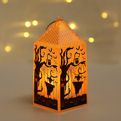 Mini Halloween lantern lit warm amber, printed with a gnarled tree face, an owl and a pumpkin-headed scarecrow