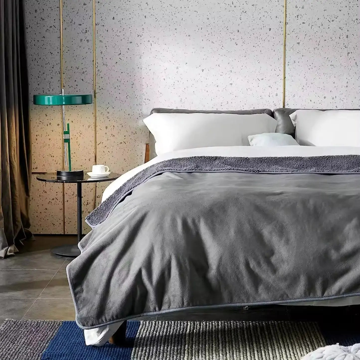Gray plush blanket spread across the foot of a made bed with the sherpa side folded back at the top
