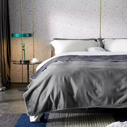 Gray plush blanket spread across the foot of a made bed with the sherpa side folded back at the top