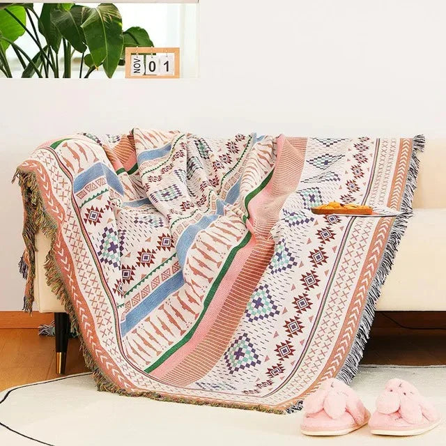 A jacquard throw striped in blush, pale blue and green through rows of small diamonds, draped over a couch