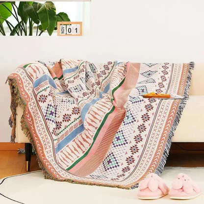 A jacquard throw striped in blush, pale blue and green through rows of small diamonds, draped over a couch