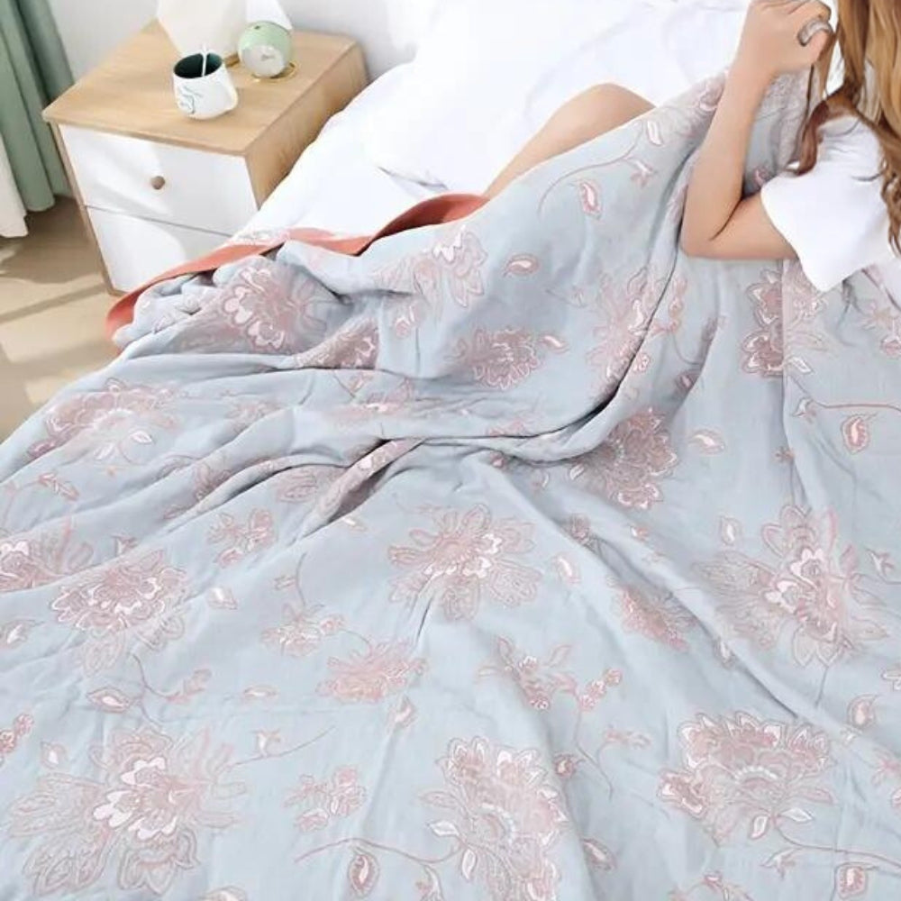 Rust throw blanket on a white bed, coral flowers woven on a soft gray face with a rust edge