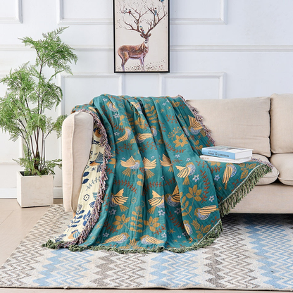 The bird throw draped over the arm and seat of a cream sofa, with the cream side running down the arm