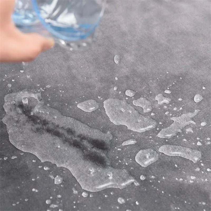Water poured from a glass sitting in beads and small puddles on the gray flannel face