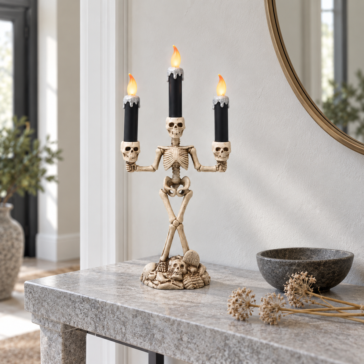 Skeleton candle holder with silver candles lit on a stone console table in a bright hallway