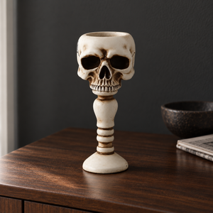 Bone skull candle holder on a walnut console table against a dark wall in daylight