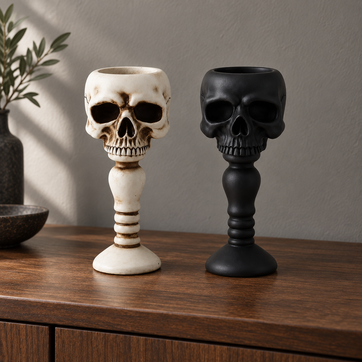 Bone and black skull candle holders standing together on a sideboard in daylight