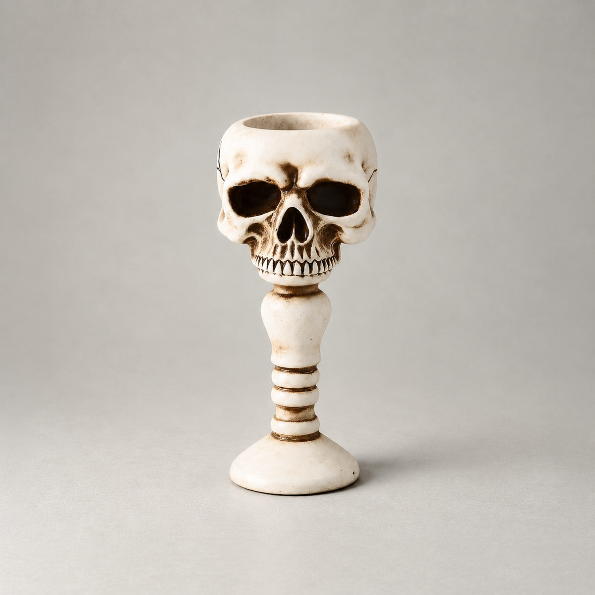 Bone skull candle holder shown front on against a plain grey studio background