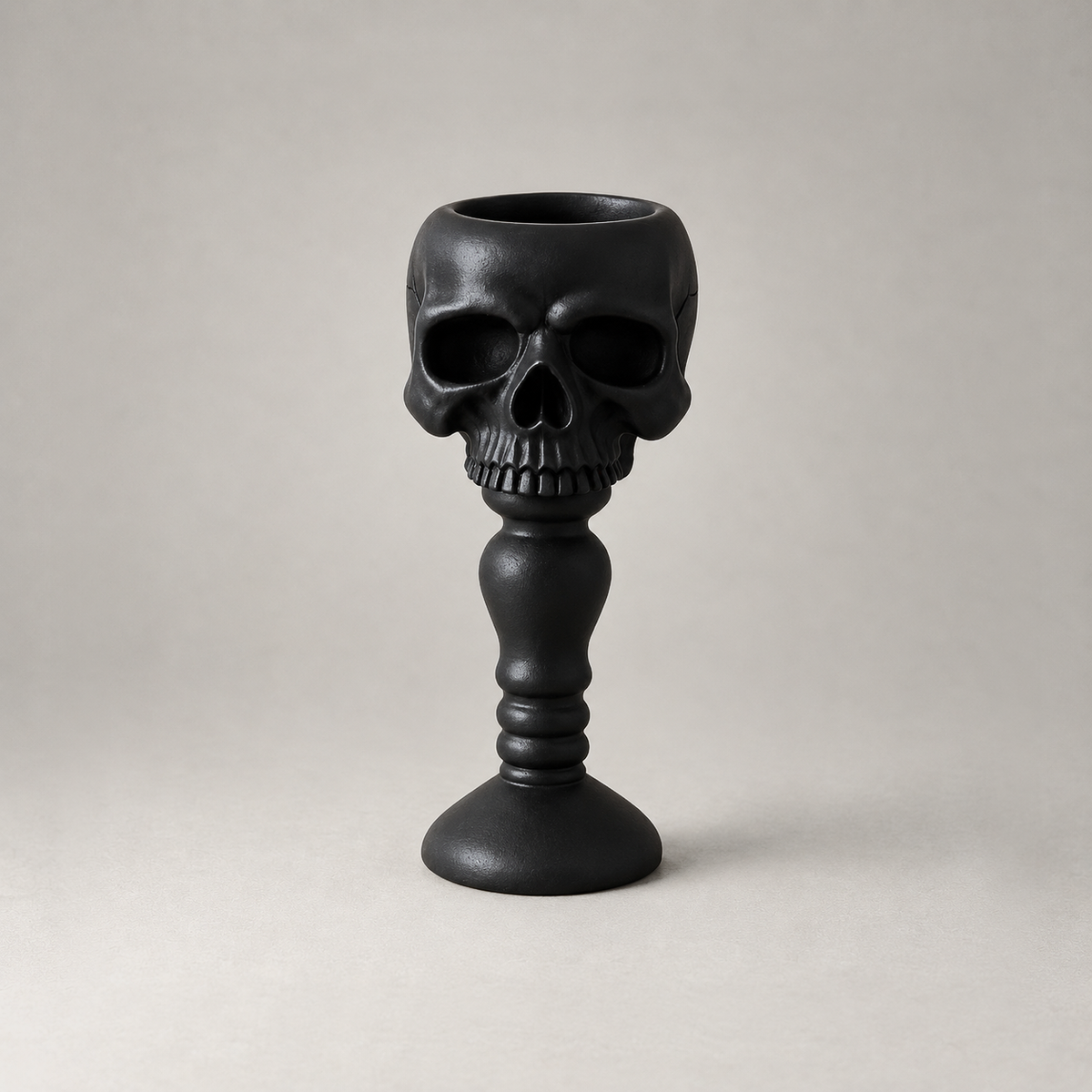 Black skull candle holder shown front on against a plain grey studio background