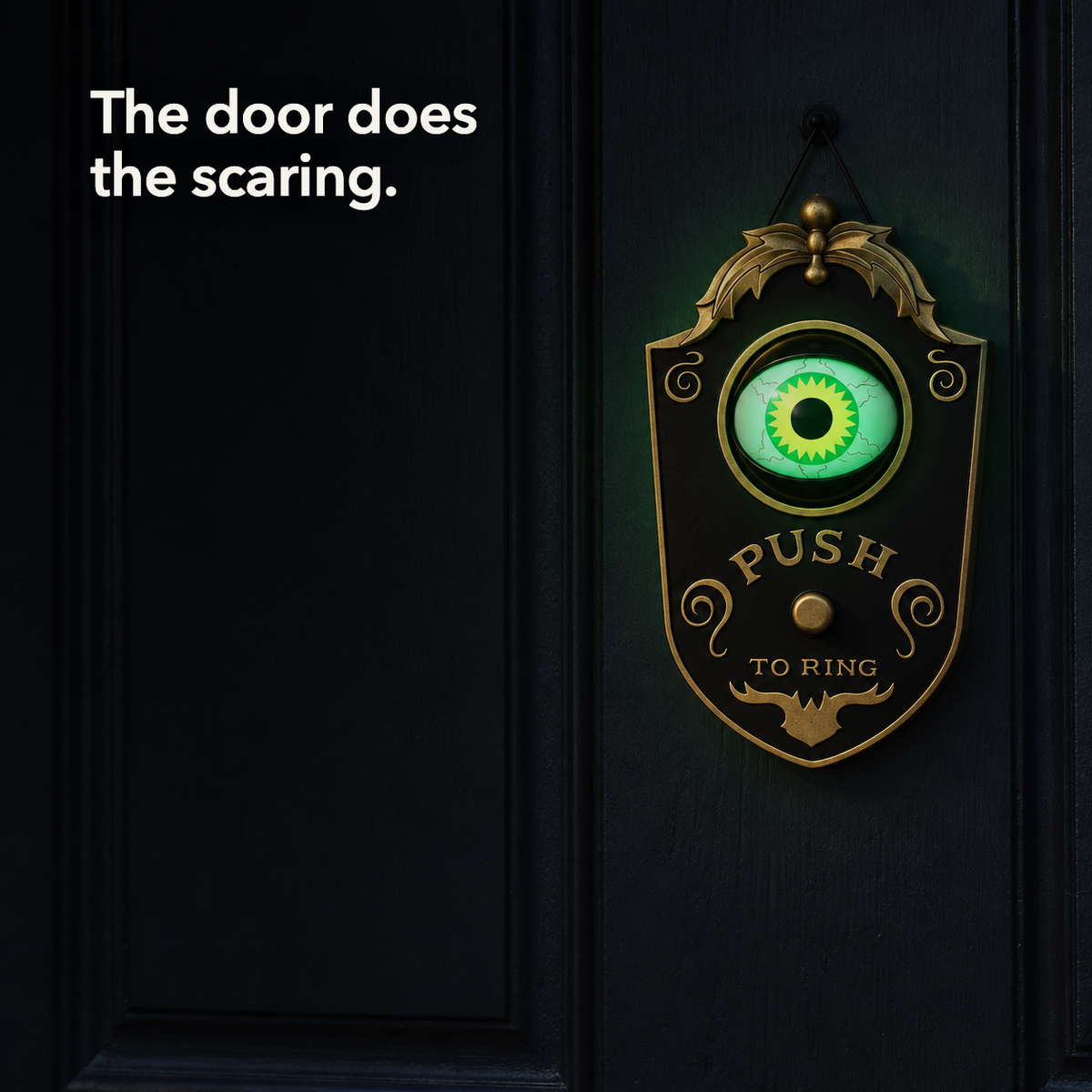 A black eyeball doorbell decoration on a dark front door with its green eye lit, and the line "The door does the scaring"