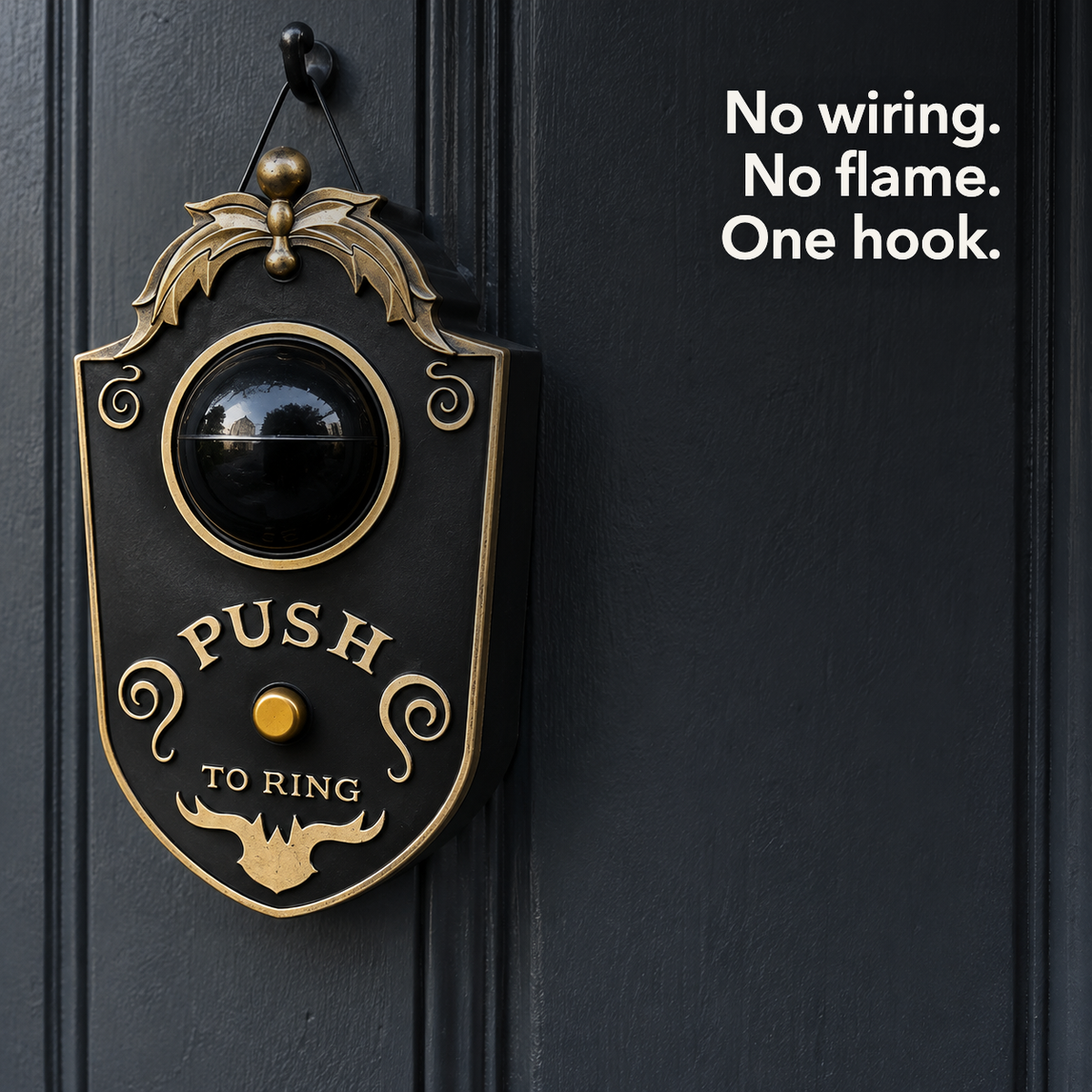 A black eyeball doorbell decoration hanging by its wire loop from a plain hook on a dark door, with the line "No wiring. No flame. One hook."