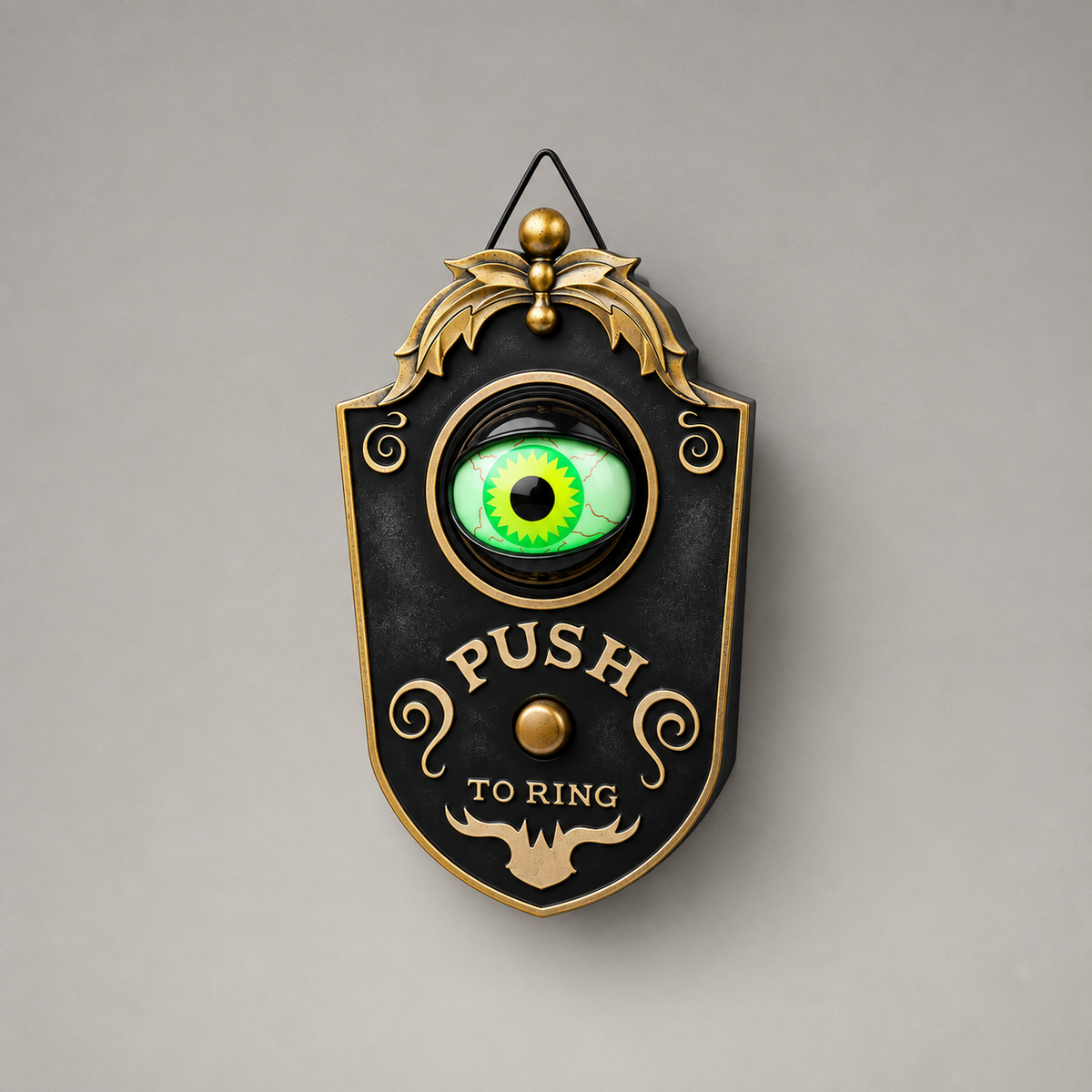 Black Halloween eyeball doorbell decoration photographed straight on against a plain grey background, its green eye lit inside a gold-toned ring