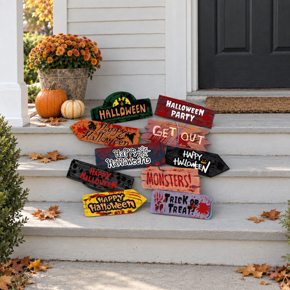 Ten Halloween signs arranged on white porch steps in daylight, beside pumpkins and a pot of orange flowers
