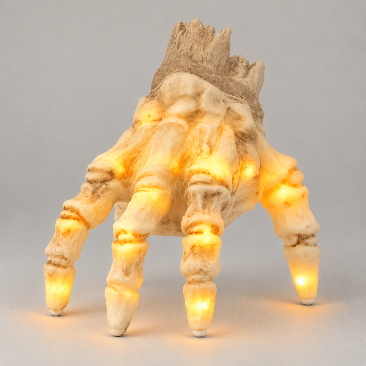 Close view of the lit skeleton hand at fingertip level, warm amber light glowing inside the knuckles and the last bone of each finger, with the wrist stump dark