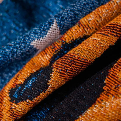 Macro of the woven cloth across a fold, with a cream star woven into the deep blue ground beside a ribbed orange band