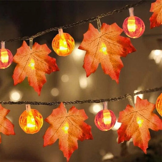 Maple leaf and pumpkin string lights lit at night, leaves and glowing pumpkin bulbs along a dark twisted wire