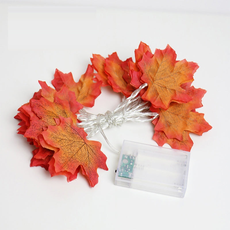 Maple leaf string lights in the leaves only style, coiled and switched off on white, showing the clear wire and the battery box