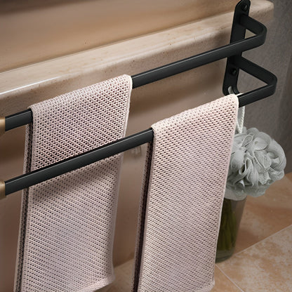 Two-bar matte black aluminum towel rack mounted below the rim of a bath, a towel on each stepped bar and a loofah hanging from a hook at the foot of the end plate