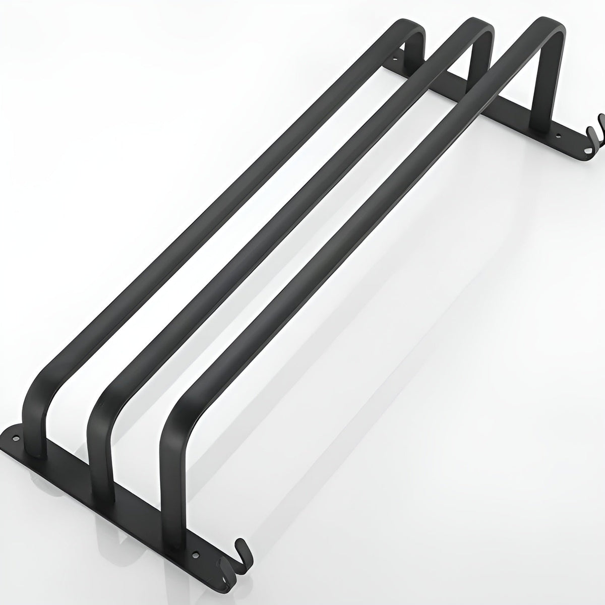 Three-bar matte black aluminum towel rack lying flat on white, each bar one continuous U between the two end plates, with a pair of small hooks at each plate