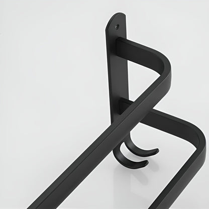 Studio close-up of a matte black aluminum towel rack end plate with two rounded bars stepping out from it and a pair of small J hooks at its foot