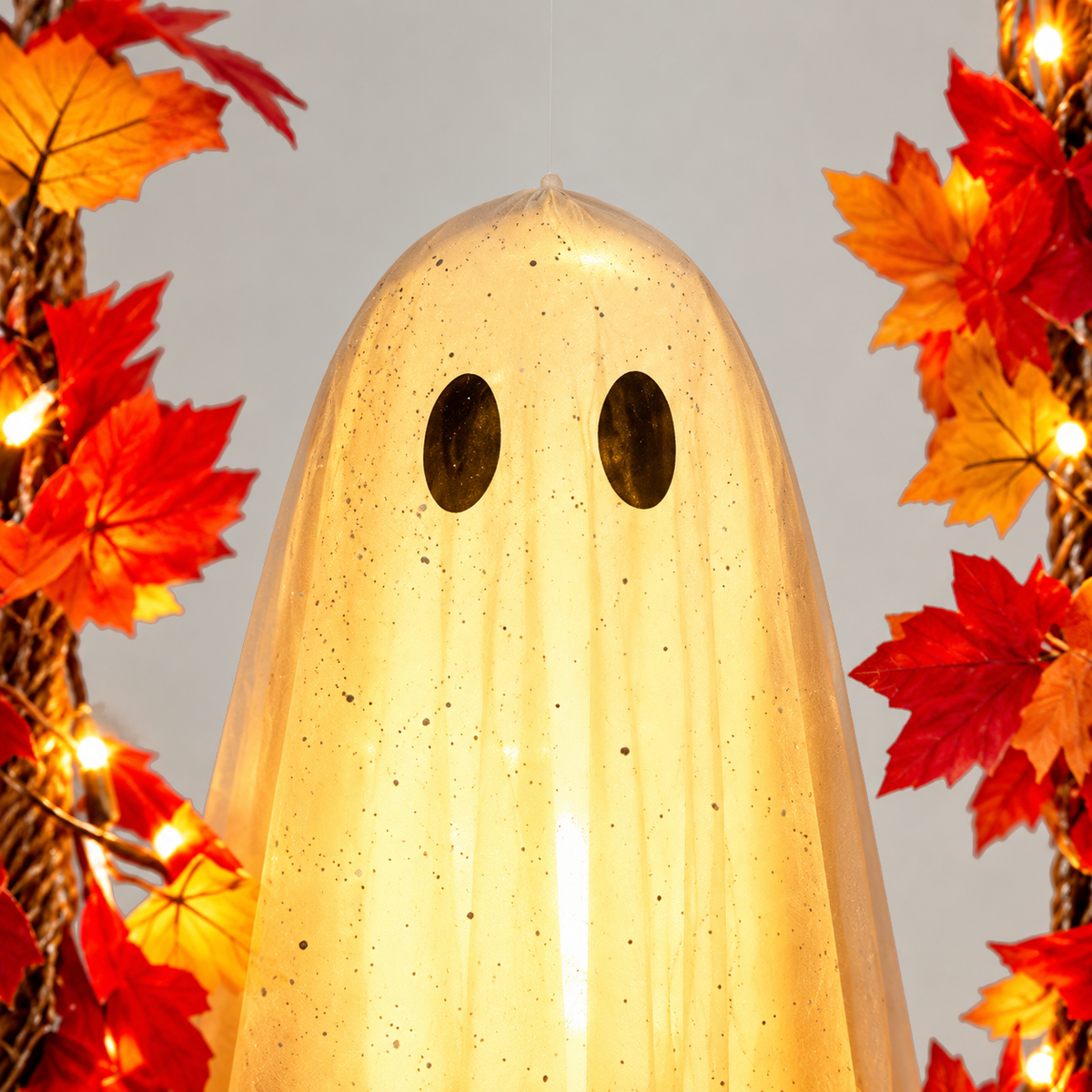 Close-up of the ghost's head showing sheer specked white fabric and two dark oval eyes, lit from inside