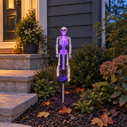 Purple solar skeleton stake light glowing in a flowerbed beside a porch step at dusk